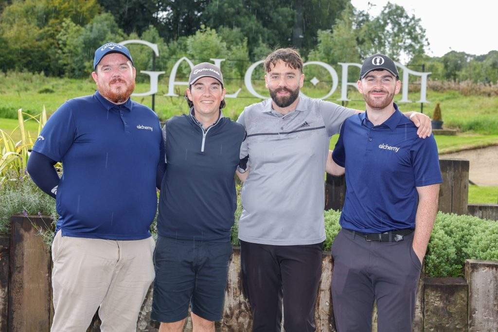 Four men standing in front of the Galgorm sign at Galgorm Castle, smiling at the camera with arms around each other. 