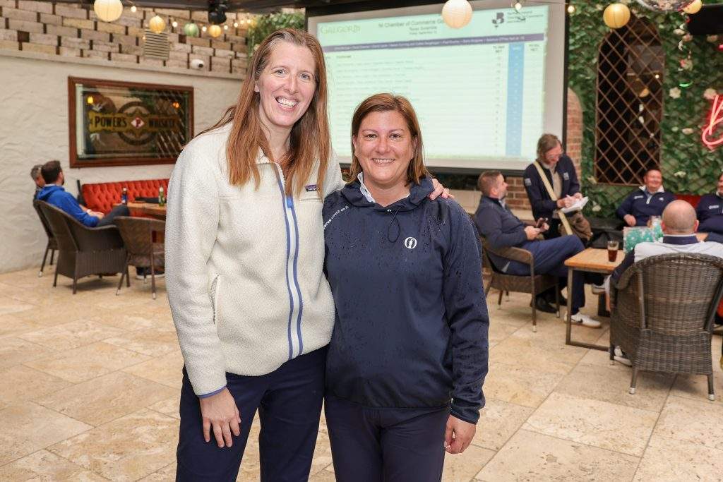 Two women standing with an arm around each other post-golf, in the Barn Bar.