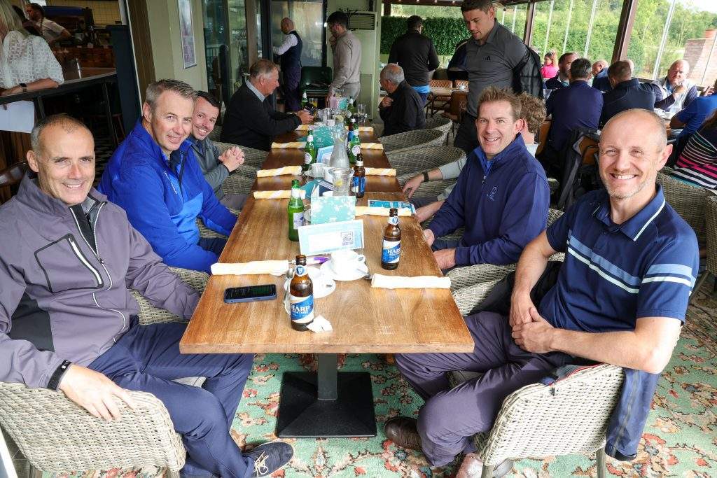 A group of people sat at a long table smiling at the camera.