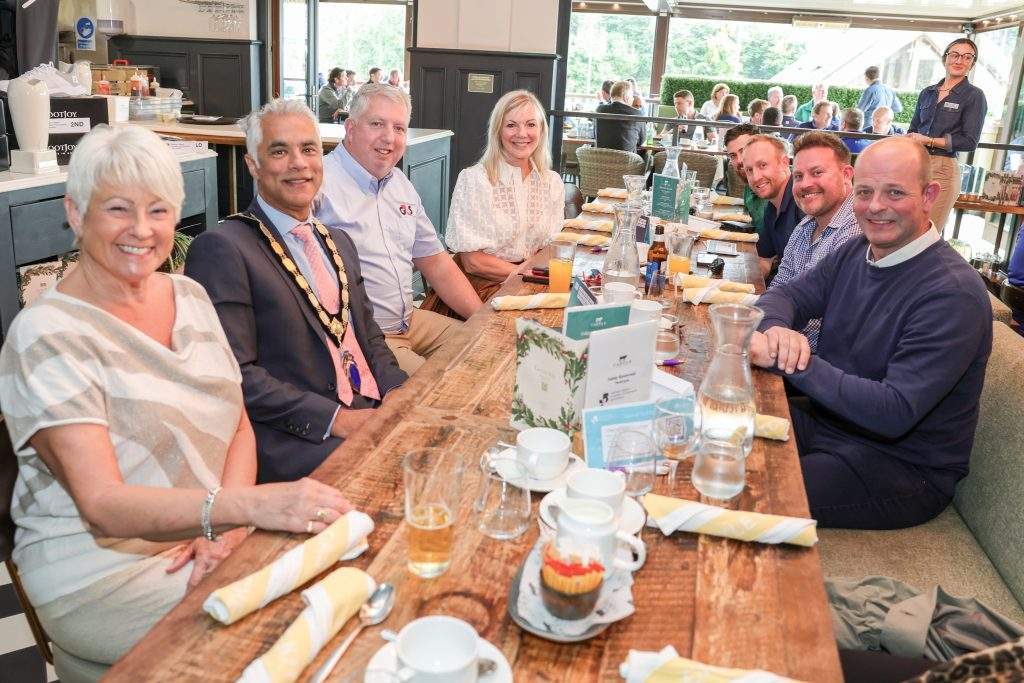 NI Chamber ceo, president, and G4S sponsor sat at a long table with 5 other people, all smiling at the camera.,