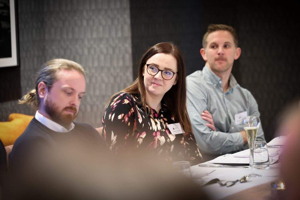 three people close to the camera all listening to someone talking