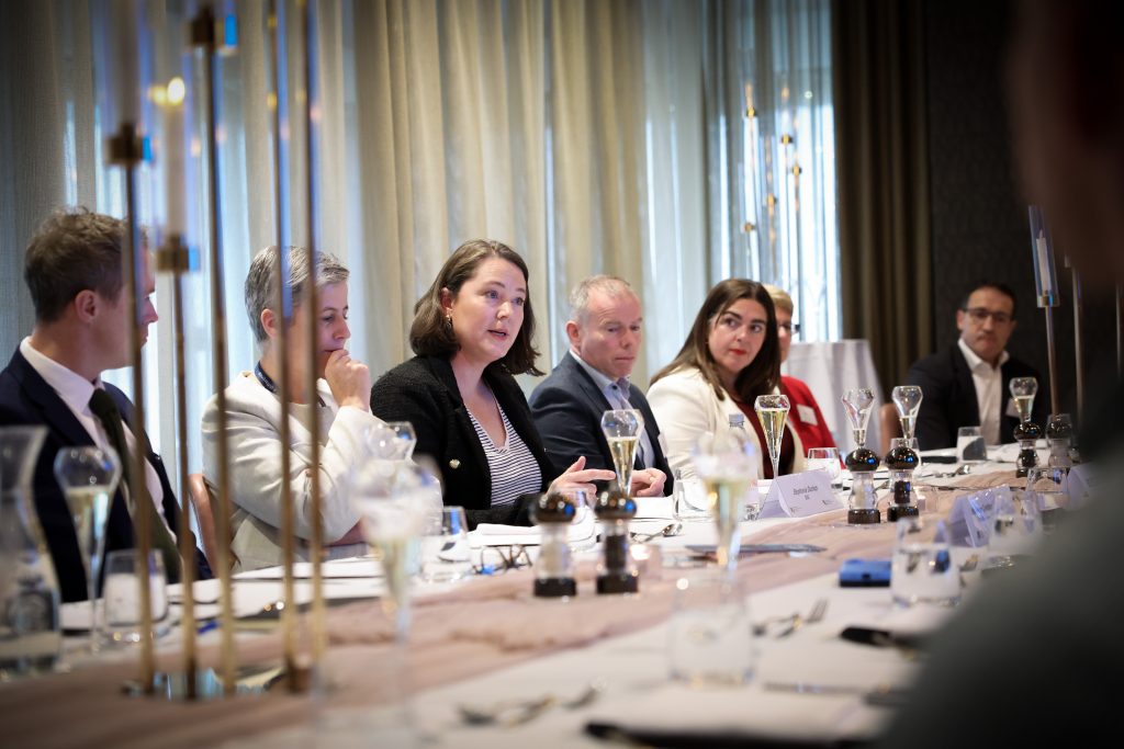 a line of four people at the table with some table decorations coming slightly in front of the camera on the left. Stephanie Dunlop, Policy Manager, SSE  speaking to someone across the table, the others engaged. 