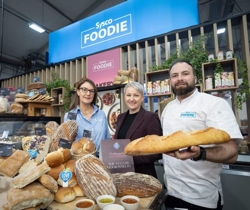 Three people standing in a bakery 