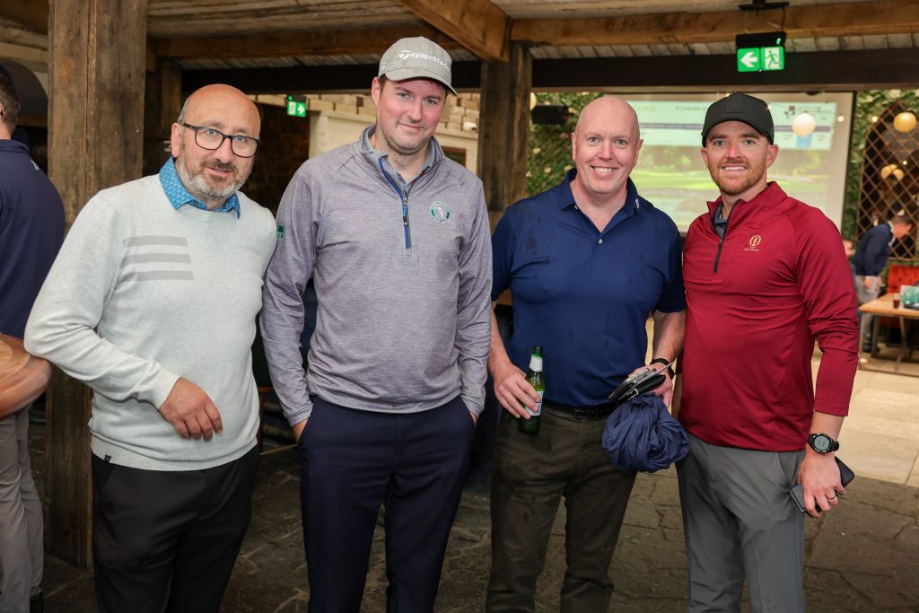 Four people standing with beers after the golf - in the Barn bar smiling at the camera.