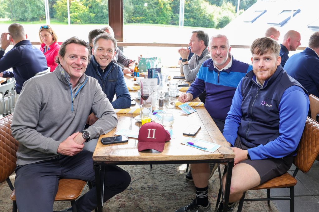 Shot of four people in the restaurant smiling at the camera sat at a table.
