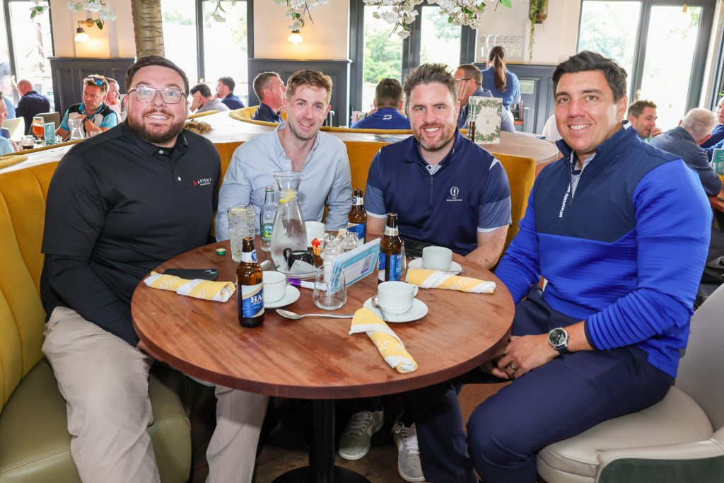 Four people in the restaurant sat at a round table smiling at the camera.