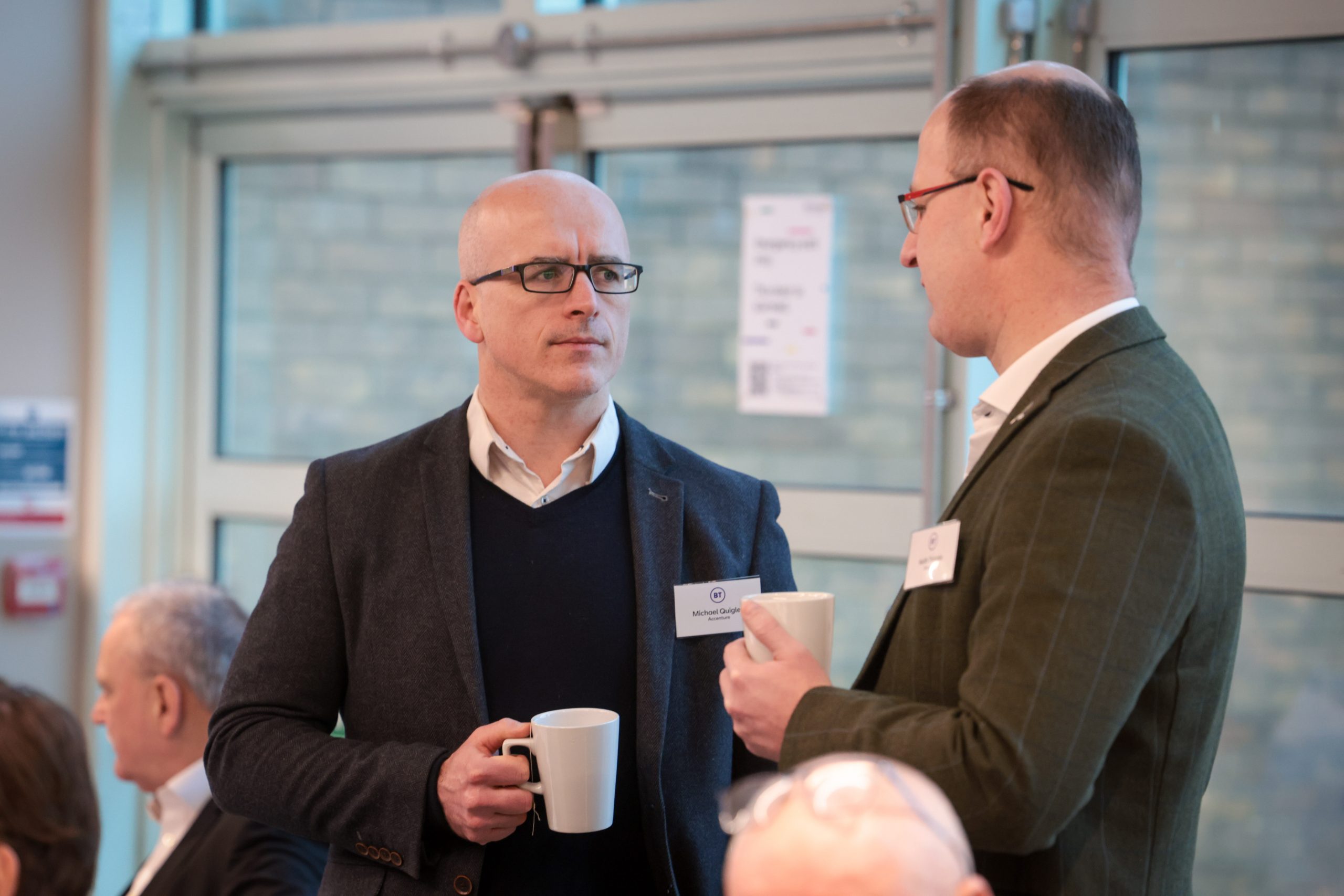 Two people chat while holding coffee cups during a networking break.
