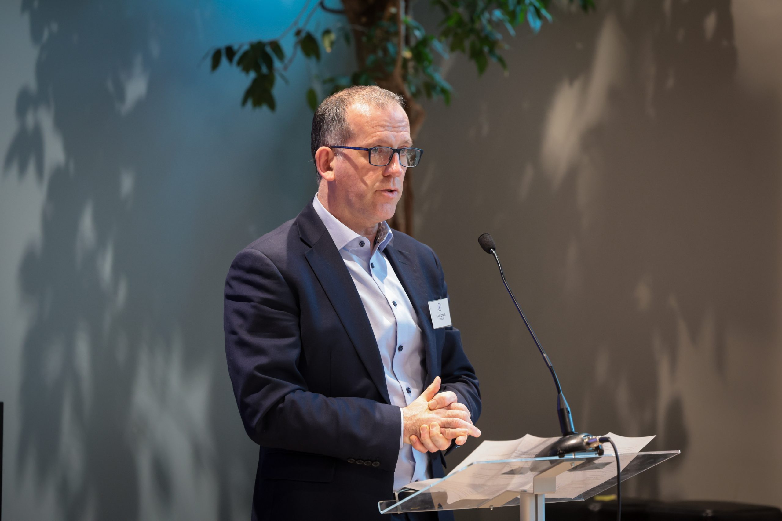 A person in a suit gives a presentation at a podium.