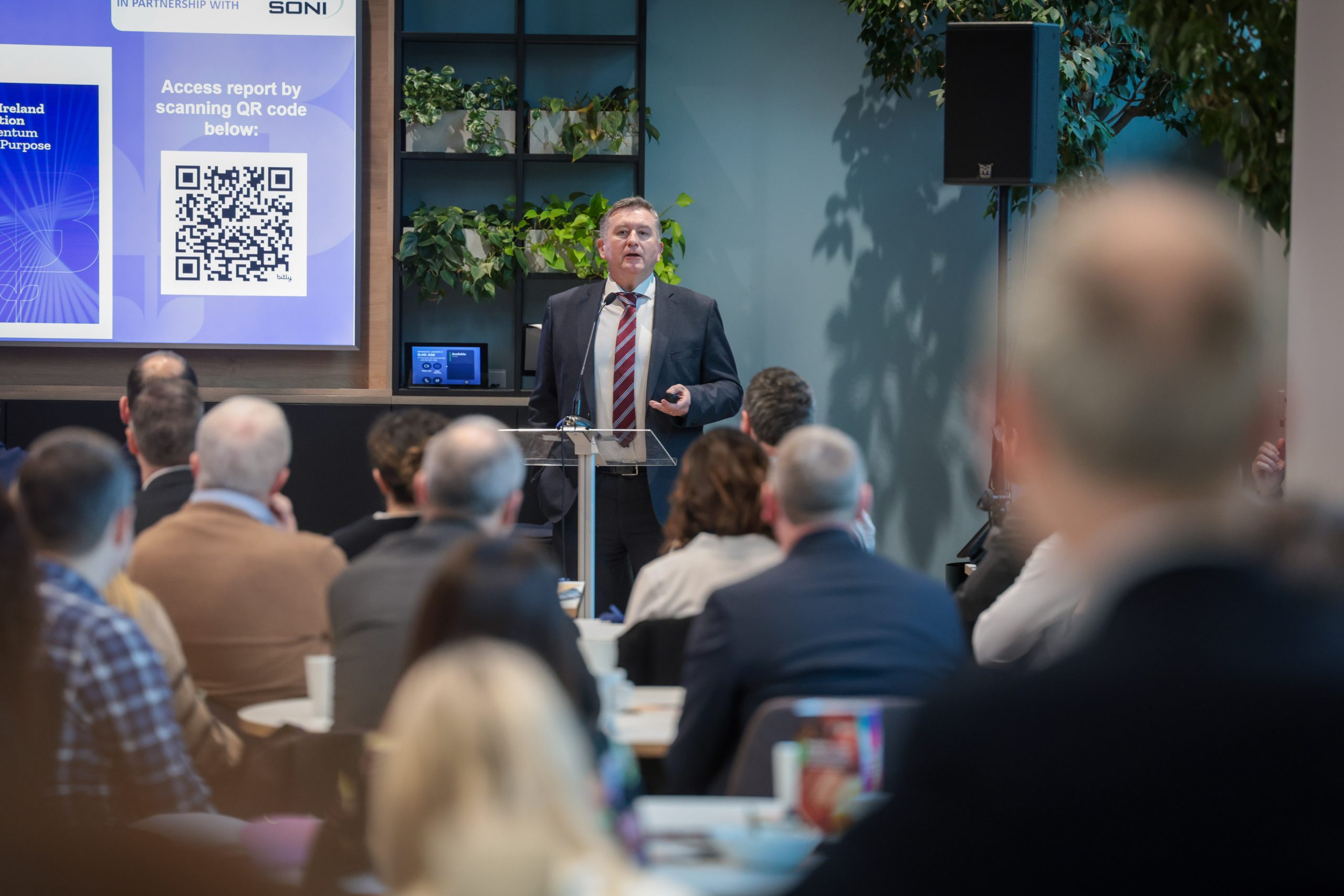 A person in a suit gives a presentation at a podium.