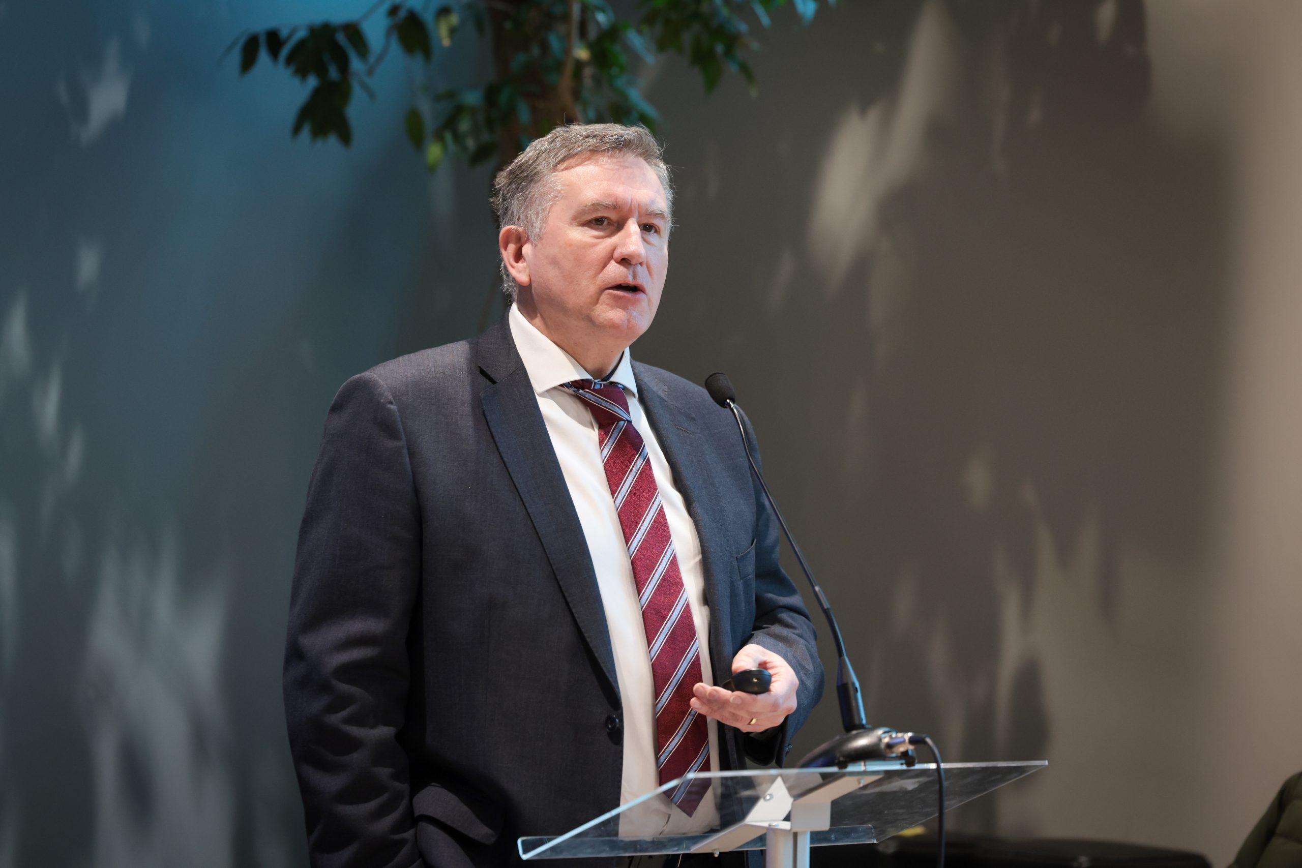 A speaker presents at a podium while attendees sit and listen.