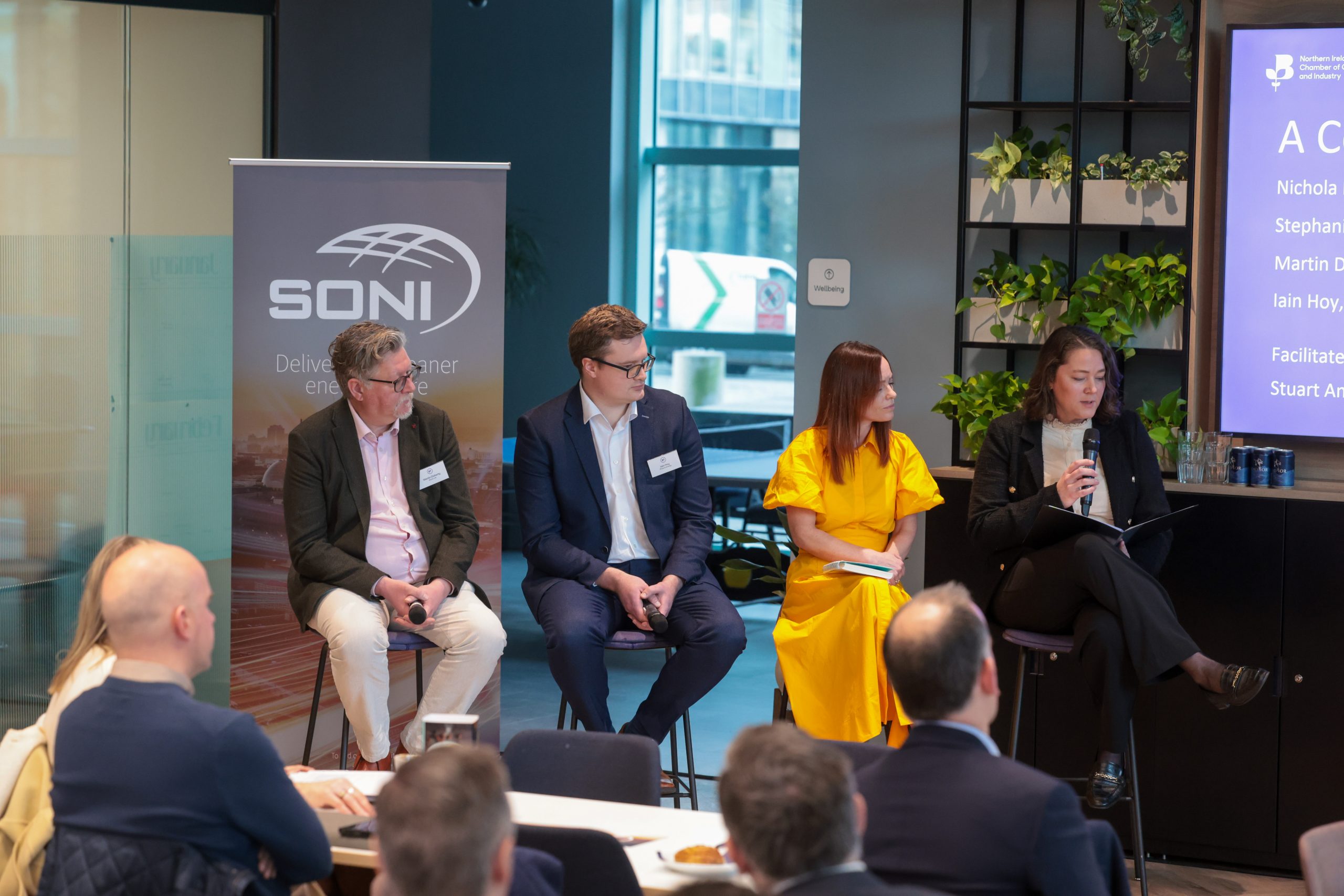 Four panelists sit on stools holding microphones during a discussion